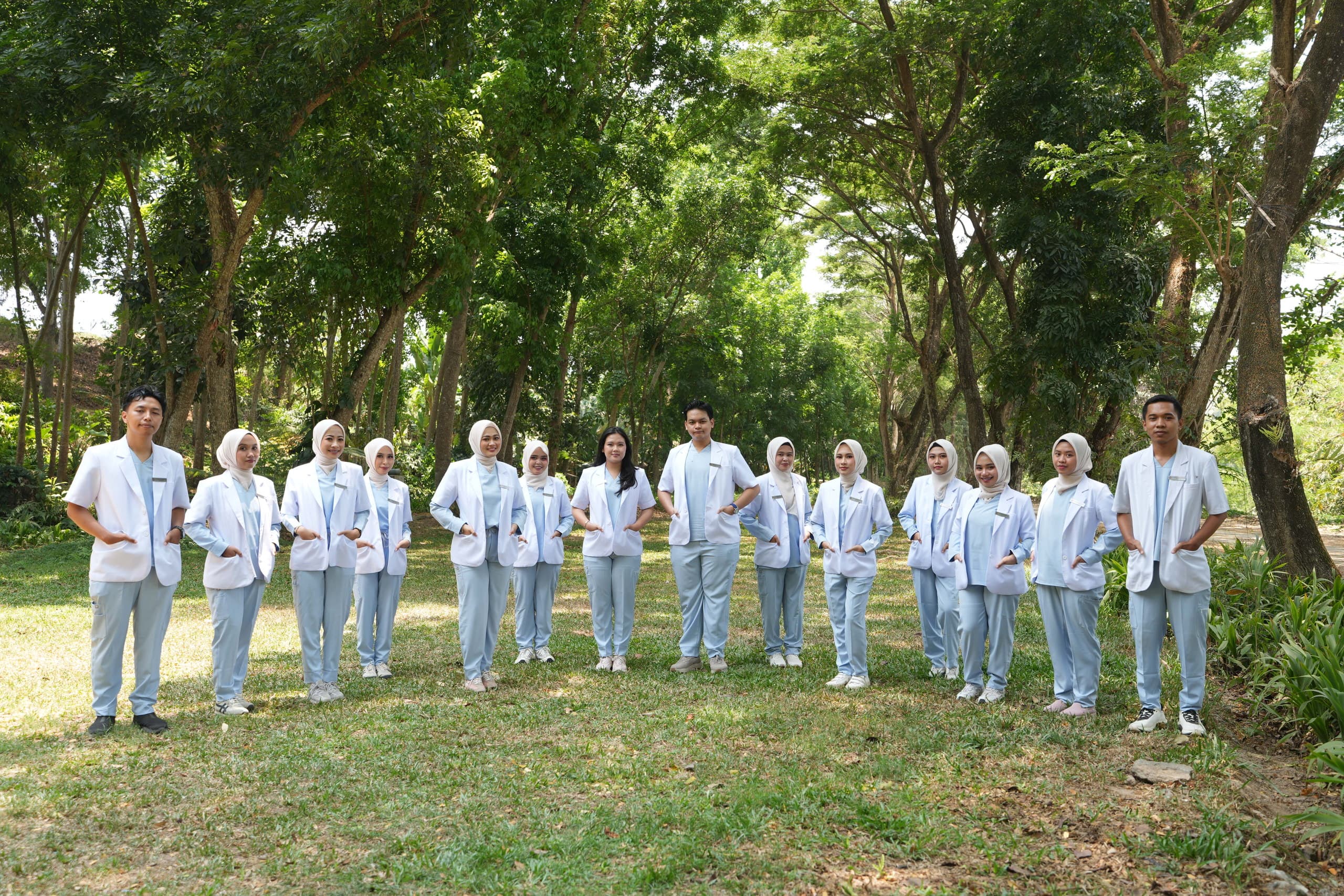 Para dokter berfoto bersama di bawah pepohonan
